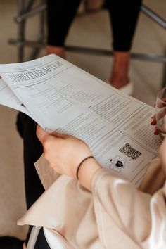 a woman sitting down reading a piece of paper with her hand on top of it