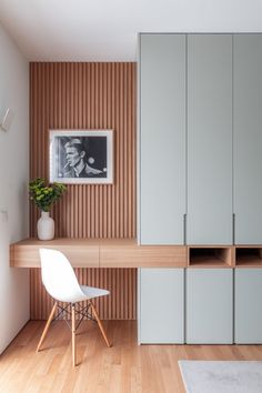 a white chair sitting in front of a wooden shelf next to a wall mounted photo