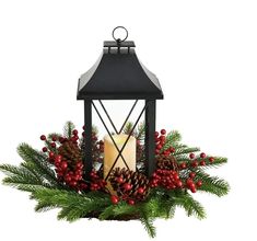 a candle is sitting on top of a christmas wreath with pine cones and red berries