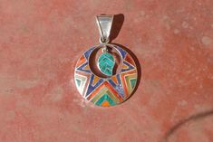 This beautiful Pendant with Coca Leaf is handmade by the beautiful Quechua people of the Peruvian Andes. It is made by 950 silver and gemstones of the region ( Lapiz Lazuli, Crystacola, spondyllus)weight : 10.4 grdiameter : 3.3 cmheight with hook : 4.8 cmIt is handmade in 950 silver with inlaid stone and shell by a local family of jewelry artesians. Green Bohemian Jewelry With Inlay, Bohemian Green Jewelry With Inlay, Bohemian Green Inlay Jewelry, Multicolor Spiritual Jewelry With Inlay, Colorful Nickel Free Bohemian Jewelry, Spiritual Multicolor Inlay Jewelry, Bohemian Jewelry With Inlay As Gift, Bohemian Jewelry With Inlay For Gift, Bohemian Inlay Jewelry For Gift