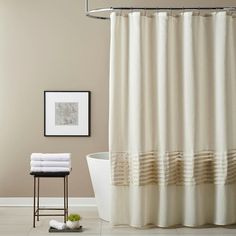 a white bath tub sitting next to a shower curtain and a framed picture on the wall