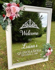 a welcome sign with flowers and greenery in front of a mirror that says welcome to lucia's quinceanera