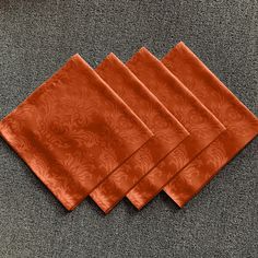 four orange napkins sitting on top of a carpet