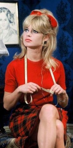 a woman sitting on top of a bed wearing a red dress and headbands