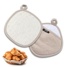 an oven mitt with croissants in it next to a basket of bread