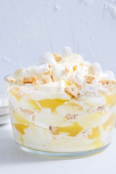 a cake with white frosting and toppings in a glass dish on a table