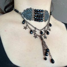 This stunning Gothic Victorian style copper choker is a true statement piece, designed to captivate and enchant. The choker features a central design adorned with symmetrical copper elements and dazzling black Czech crystals. Two elegant layers of chains cascade down, embellished with charming copper stars and teardrop-shaped crystals, adding a touch of mystique and elegance. The ends of the layered chains are finished with tassels, each adorned with additional crystals, enhancing the overall al Handmade Black Steampunk Necklace, Adjustable Black Steampunk Choker, Gothic Festival Choker Jewelry, Black Bohemian Choker With Adjustable Chain, Steampunk Black Choker Jewelry, Gothic Metal Choker For Festivals, Gothic Choker Necklace For Jewelry Making, Steampunk Choker Jewelry Gift, Steampunk Metal Necklaces For Festivals