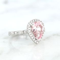 Elegant Vintage Inspired Pink Sapphire Ring ►Made of solid sterling silver with rhodium finish (925) ►Accented With Simulated Diamonds (CZ) ►Average band width: 2 mm Center Stone: Sapphire Color: Pink Shape: Teardrop Gem size: 7.0 x 10.0 mm Carat Weight: 2 ct. (approx.) Gemstone creation: 100% Natural Hardness: 9-9.5 (Mohs scale)- tests like a natural diamond ►Due to the gemstone nature, color of the gem may slightly vary. ✓ 100% Nickel-Free ✓ Hypoallergenic ✓ Comfort Fit ✓ Free Ring Box ✓ Free White Gold Teardrop Jewelry For Proposal, Classic Pink Halo Ring, Classic Proposal Jewelry With Accent Stones, Classic Halo Design Jewelry For Proposal, Classic Jewelry For Proposal With Accent Stones, Silver Halo Teardrop Rings, Silver Teardrop Halo Rings, Classic Teardrop Diamond Ring With Accent Stones, Teardrop Solitaire Ring For Proposal