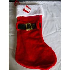 a red and white christmas stocking with a gold buckle on the front, sitting on a bed