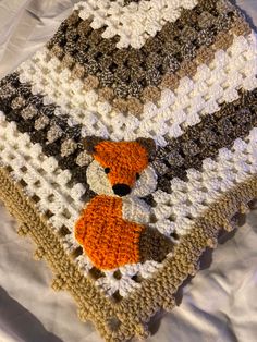 a crocheted blanket with a teddy bear on it and an orange fox in the center