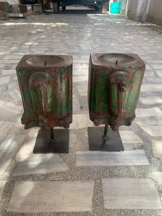 two candles are sitting on pedestals in the middle of a courtyard with tile flooring