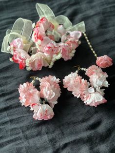 pink and white flowers on black fabric with pearls hanging from the end of each flower