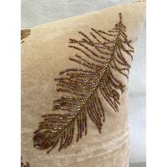 a decorative pillow with beaded feathers on it