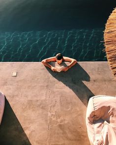 a man laying on top of a cement slab next to the ocean with his hands behind his head