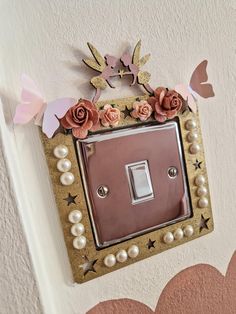 a decorative light switch cover with pink flowers and butterflies on it, hanging from the wall