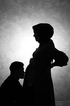 a man and woman standing next to each other in front of a light that is shining on the wall