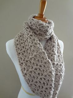 a gray crochet scarf on a mannequin headpiece with a wooden hanger