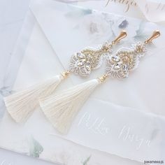 two white tassels with gold accents on top of a piece of paper next to a