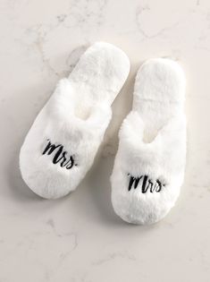 Your feet will thank you for kicking off your shoes and sliding into Shiraleah's "Mrs". Slippers. Features a plush texture upon a rubber bottom making them cozy yet sturdy. Closed toed with a "Mrs" text embroidery will adds a bit of playfulness to your newlywed lounge wardrobe. Color: Ivory Fits Size 6-8 Polyester And Pvc Made In China Vegan Ribbon Packaging 33-28-046 Comfortable Soft White Slippers, Comfy Soft White Slippers, Comfy Non-slip White Slippers, White Super Soft Indoor Slippers, Cozy White Slippers With Plush Lining, Comfy White Closed Toe Slippers, White Fluffy Slippers With Round Toe, White Super Soft Comfy Slippers, Cozy White Non-slip Slippers