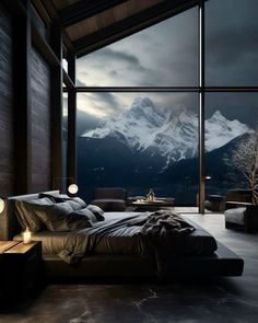 a bedroom with a large window overlooking the mountains and snow capped peaks in the distance