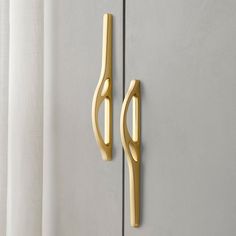 two gold handles on the side of a white door with curtains in the back ground