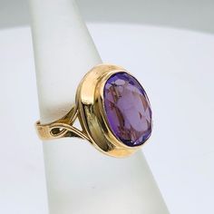 Elegant 9 carat gold ring set with one oval   Synthetic Amethyst with dimension 10 mm x 15 mm Size of the ring is L 1/2 (US Size 6) Weight of the ring 5.58 grams Oval Yellow Gold Amethyst Ring With Polished Finish, Oval Amethyst Ring In Yellow Gold With Polished Finish, Oval Faceted Rings In Fine Jewelry Style, Classic Purple Cabochon Rings, Oval Cabochon Amethyst Ring, Oval Amethyst Cabochon Ring, Classic Oval Purple Amethyst Ring, Classic Amethyst Oval Cabochon Ring, Classic Oval Amethyst Ring