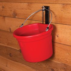 a red bucket hanging on the side of a wooden wall