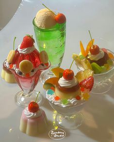 three desserts in small glass dishes on a white table top with ice cream and fruit