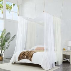 a white bed sitting in a bedroom on top of a hard wood floor next to a window