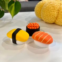 four sushi shaped objects sit on a table next to a stuffed animal and plant