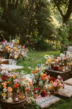 a bunch of flowers that are sitting in the grass near some bags and blankets on the ground