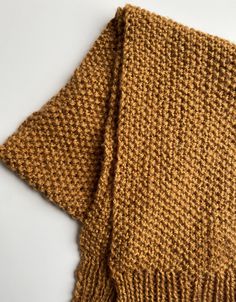 a brown knitted scarf laying on top of a white surface