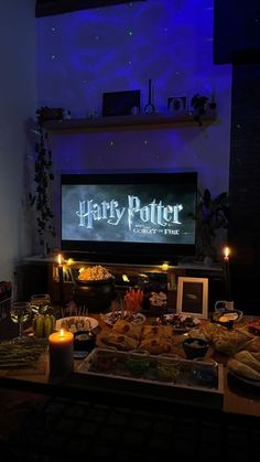 a harry potter party is set up with food and candles in front of the tv