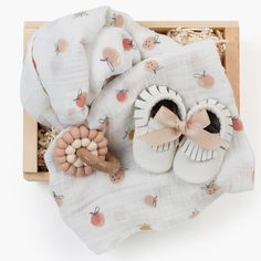 the baby's shoes and blanket are on display in a wooden box with white fabric