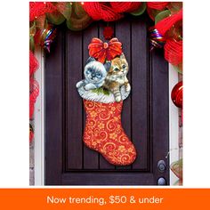 a christmas stocking with two cats hanging from it's side on a door