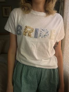 a woman standing in front of a window wearing green shorts and a white t - shirt