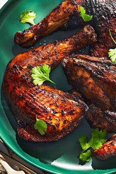 grilled chicken legs with cilantro garnishes on a green plate