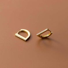 With its modern contemporary design, this pair of huggie earrings are a suitable and trendy option for fashionistas. These earrings break away from the traditional circle hoop huggies and are constructed with a one sided flat bar “D” shape design, giving it its unique appearance. What��’s more is they are made with solid sterling silver with an optional 18K gold plated option available. Details:Metal Type: Sterling SilverGemstone: Cubic ZirconiaEarring Size: 12mm * 1mmPlating: 18K Yellow Gold/Rhod Huggie Earrings Gold, Wedding Studs, Gold Earrings Designs, Cubic Zirconia Earrings, Cz Earrings, Zirconia Earrings, Huggie Earrings, Huggie Hoop Earrings, Small Earrings