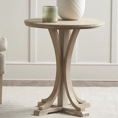 a white vase sitting on top of a wooden table next to a chair in a room