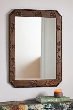 a mirror sitting on top of a dresser next to a book