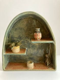 an arch shaped shelf with pots and plants on it's sides, against a white background