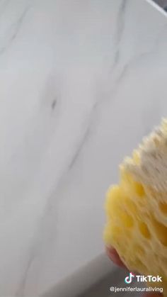 a close up of a person's hand holding a piece of bread with cheese on it