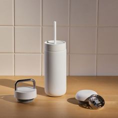 a white cup with a straw sticking out of it next to a toothbrush holder