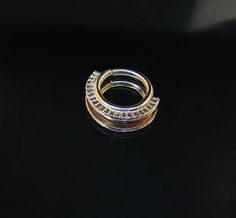 two gold rings sitting on top of a black surface with one ring in the middle