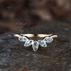 a gold ring with blue topazte and leaves on it sitting on a rock