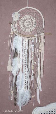 a white dream catcher hanging on the wall next to a wicker chair and pink wall