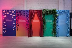 four different colored partitions in front of a brick wall with plants growing on them