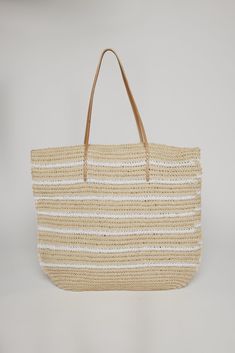 Meticulously crafted from natural raffia straw complemented by leather handles. This spacious tote seamlessly blends style and functionality, offering ample room for all your essentials. Whether you're strolling through the market or heading to the beach, this versatile accessory adds a touch of laid-back sophistication to any ensemble. Velvet Tees, Striped Bags, Easy Travel, Travel Collection, Leather Handles, Medium Bags, Large Bags, Beach Bag, Leather Handle