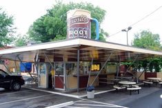 an old gas station with picnic tables in the parking lot