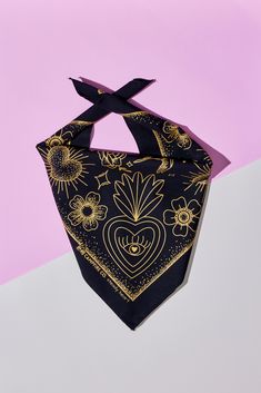 a black and gold bandana on a pink and white background with sunflowers